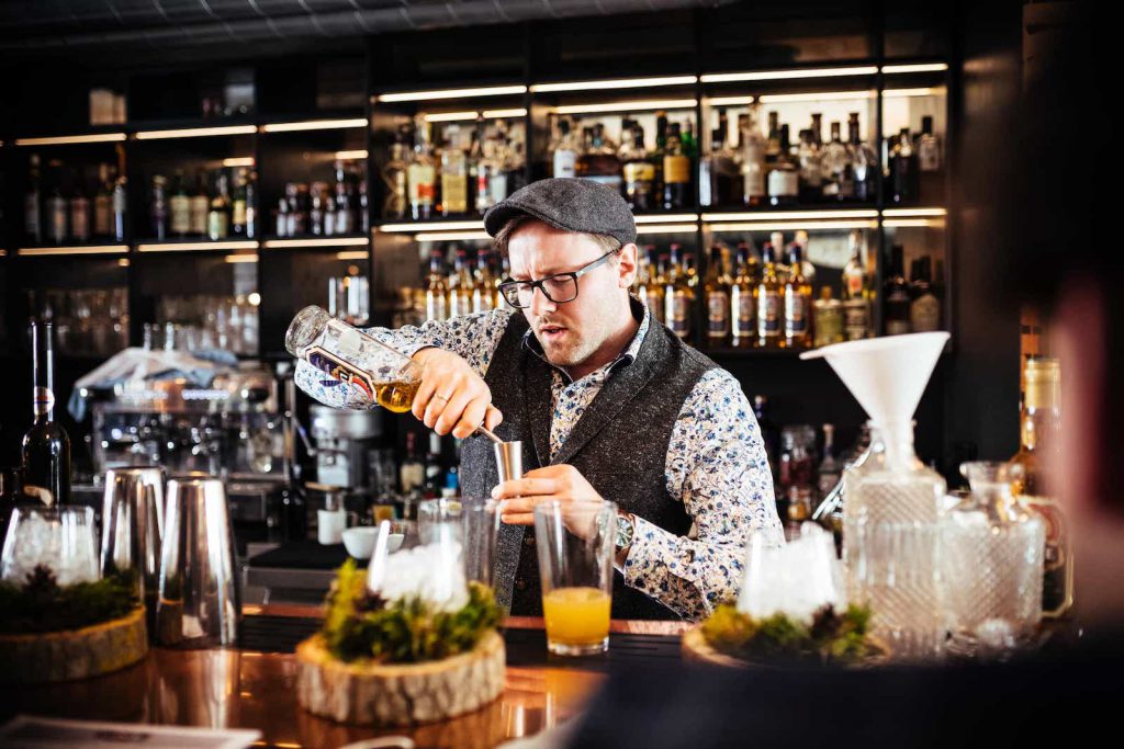 Barkeeper mist Spirituosen für einen Cocktail ab
